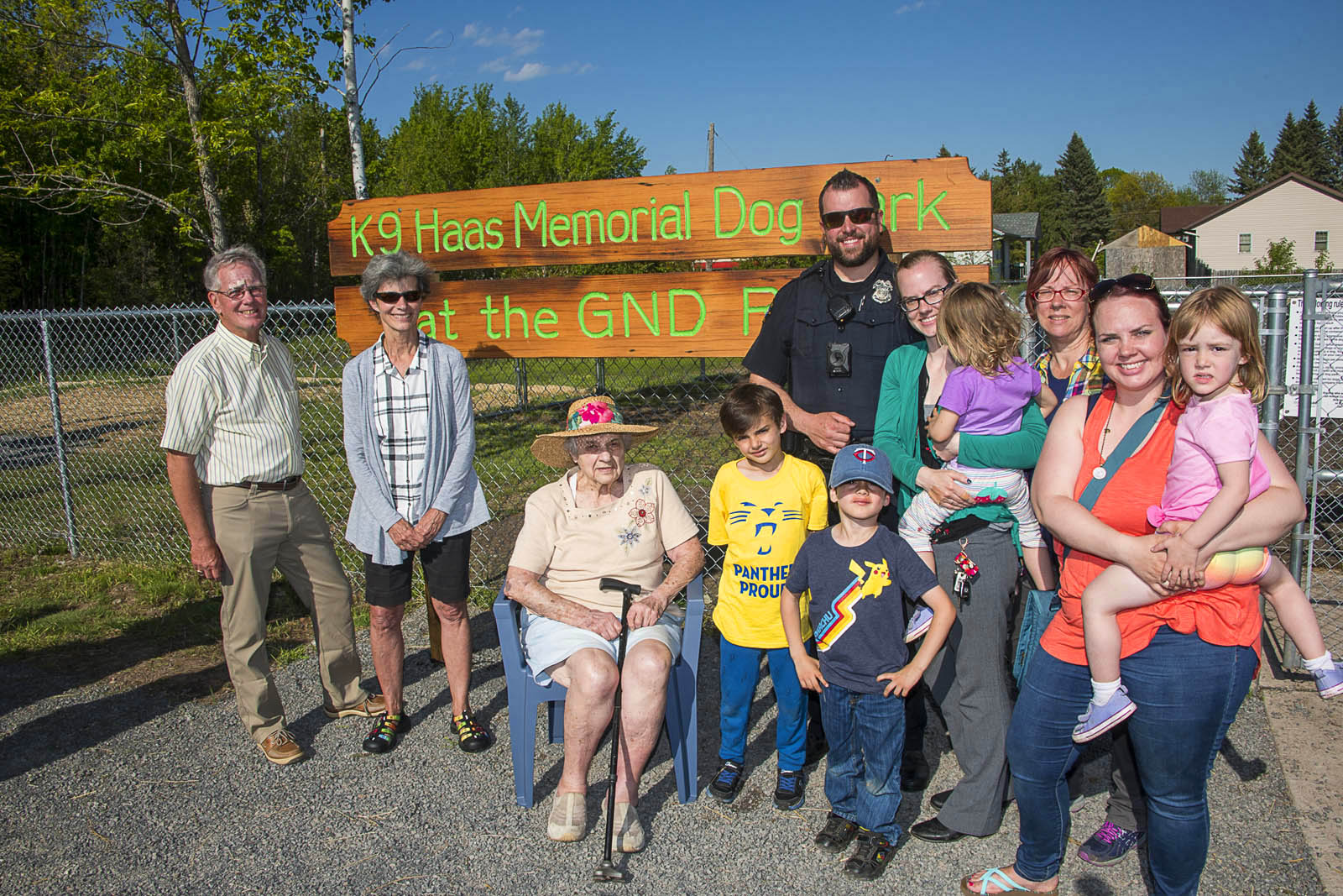 A group of people smile in front of a sign that says K9 Haas Memorial Dog Park at the GND REC