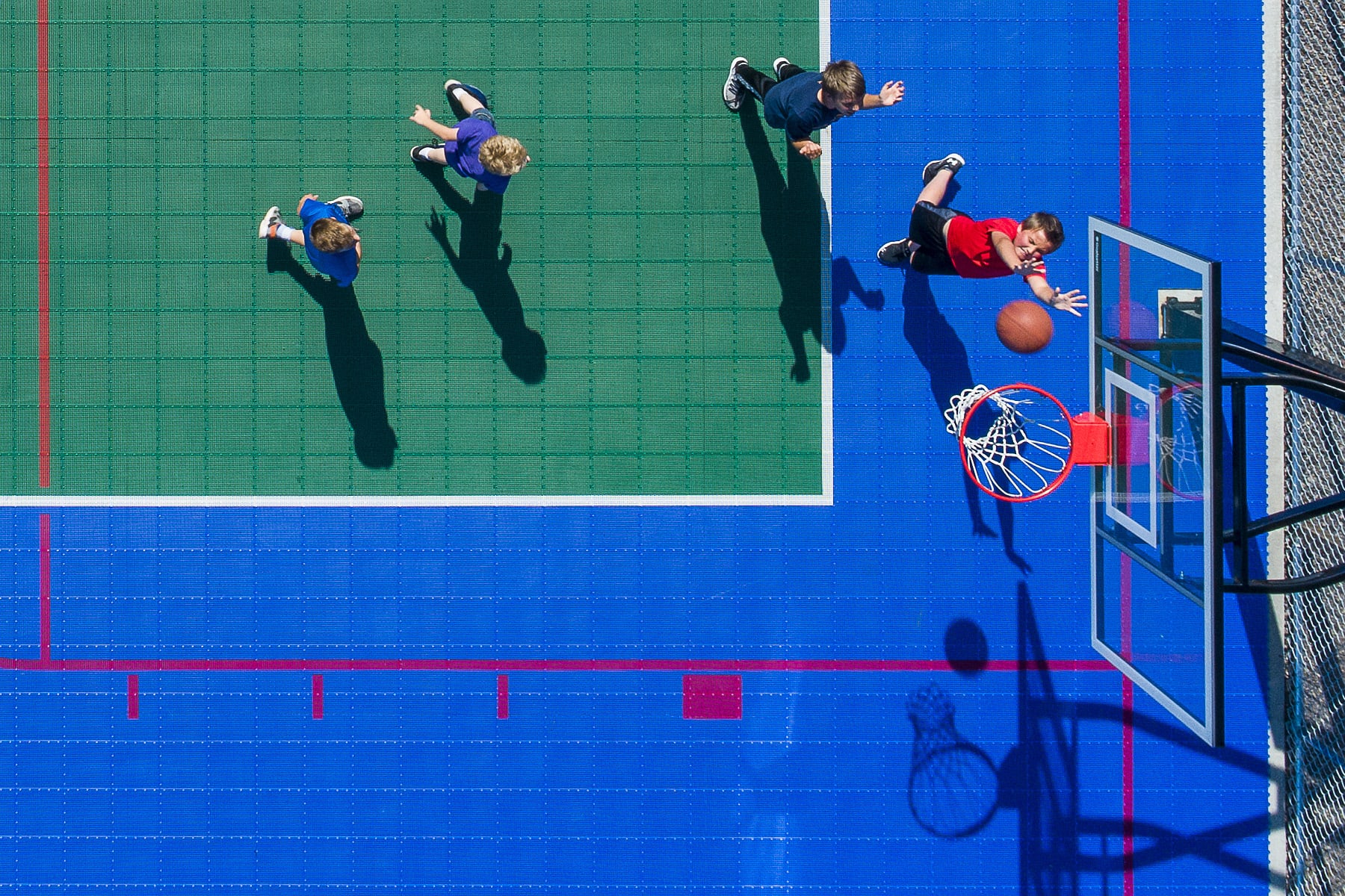 Overhead shot of a group of young boys playing basketball on a green and blue court