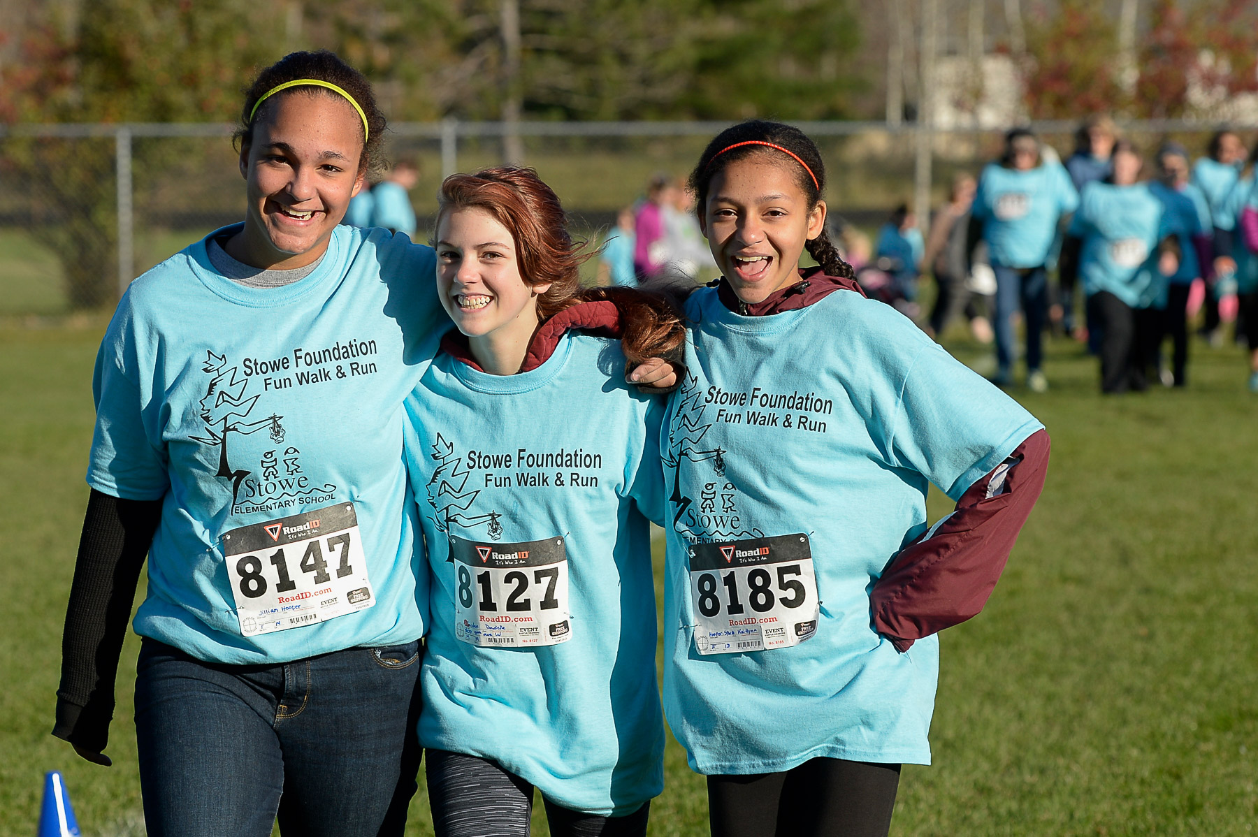 Three girls smile while wearing blue shirts that say Stowe Foundation Fun Walk & Run