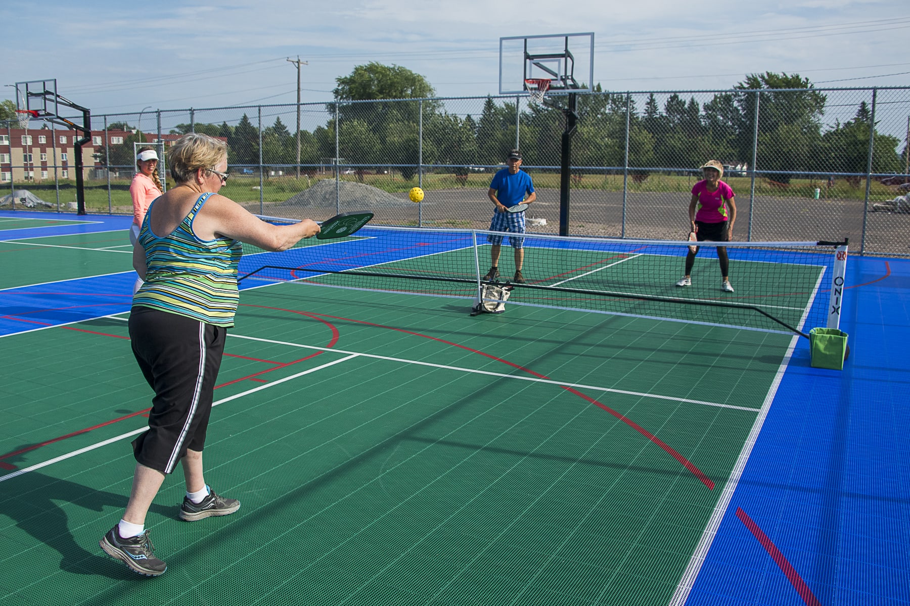 A group of four people playing pickleball on a sunny day at the Sport Court