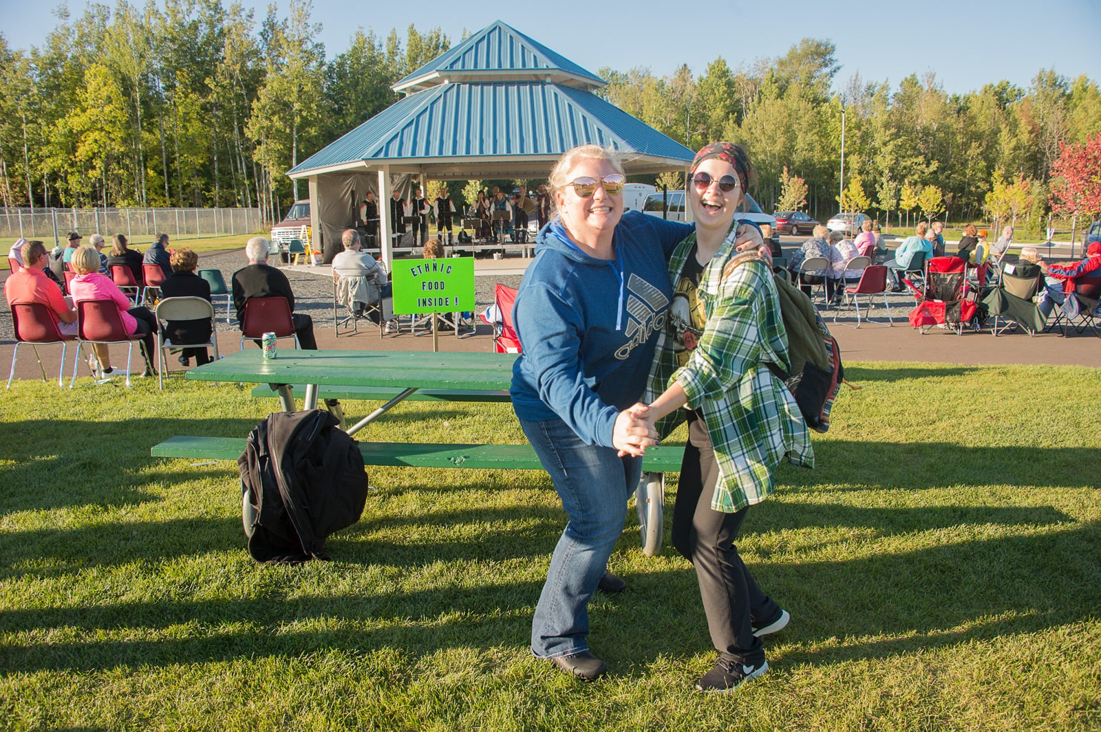 Two women dance at the Pavilion at the GND REC while smiling with a crowd behind them